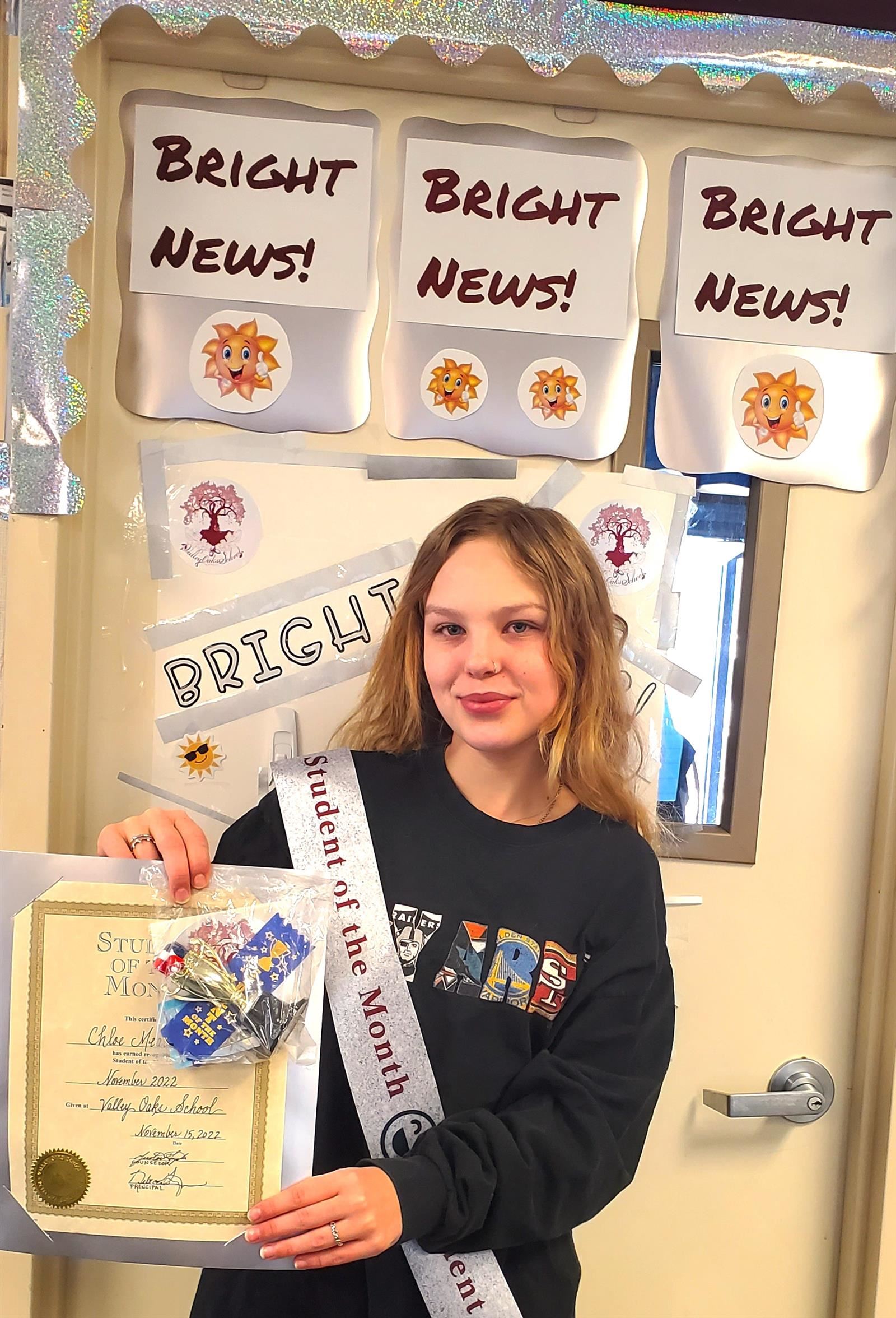  student in front of the Bright News! door smiling