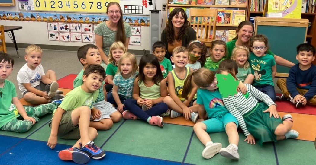 A TK Class sitting on the rug and wearing green clothing 