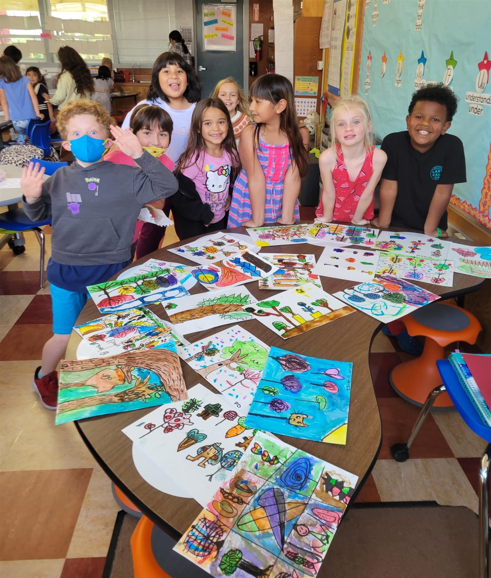 2nd Graders crowd around a table of drying watercolor projects.