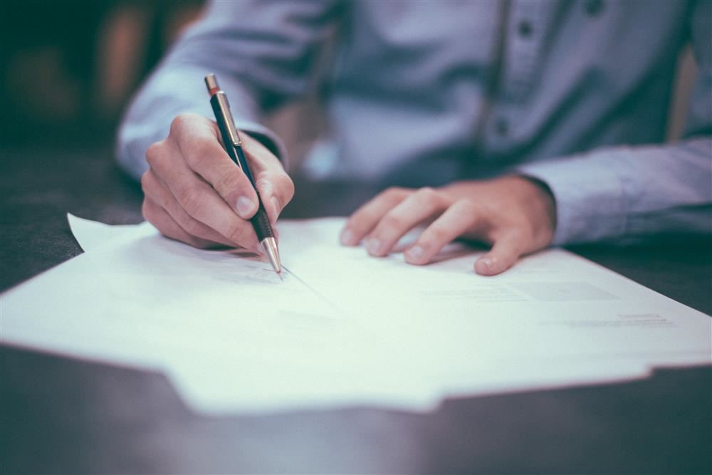 Person writing with pen and paper