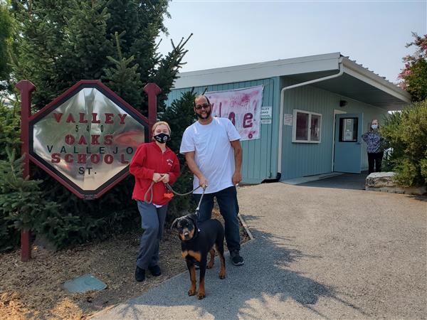 a new student, her dad and her dog in front of school