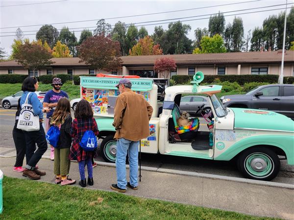 Vintage ice cream truck at a school event with customers.