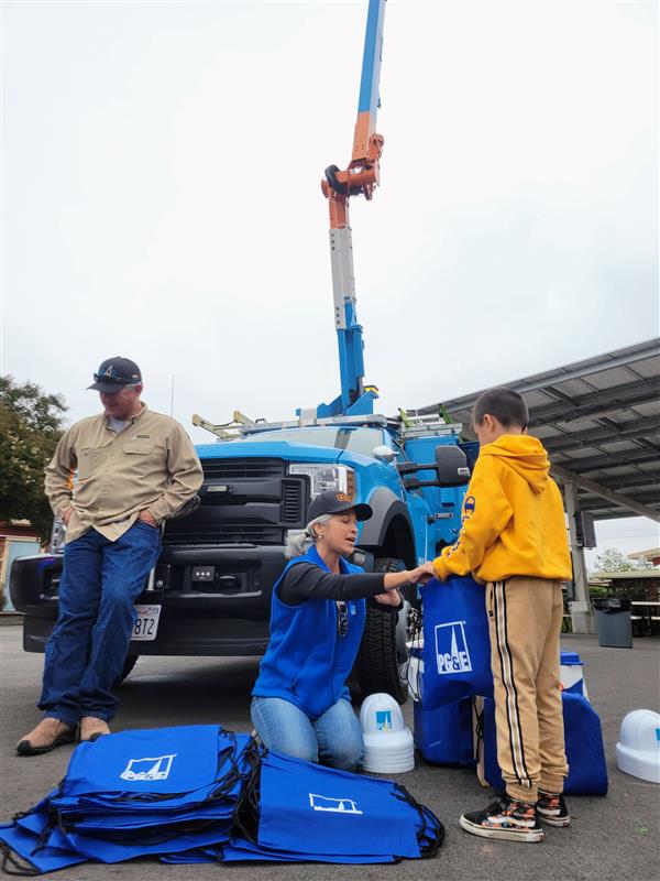 PG&E truck with its bucket extended high at a school event.