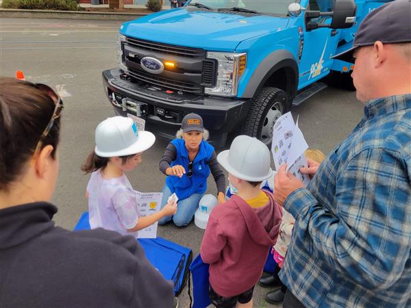 Woman PG&E worker talks to children at a school event.