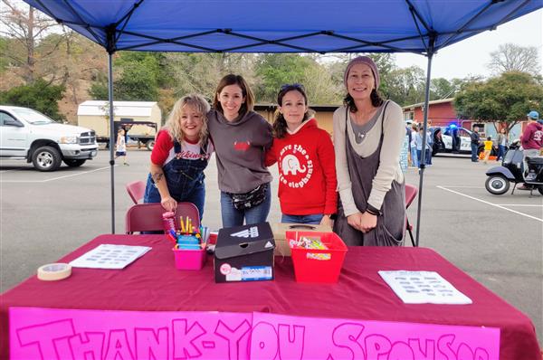 4 Awesome PTA volunteers behind a table at a school event.