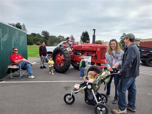 Happy families with a red tractor at a school event.