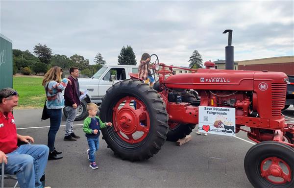 Kid sitting on a red tractor at a school event. 