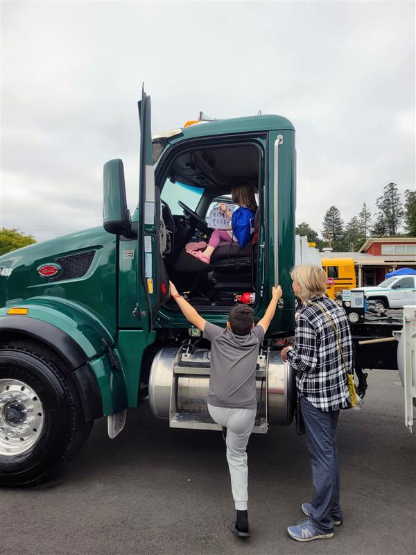 Kids climb into a semitruck cab at a school event.